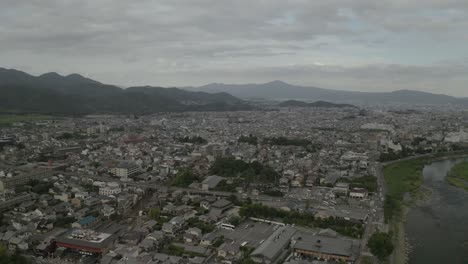 Aerial-Drone-Shot-of-Kyoto-at-Sunset-near-a-river,-Japan,-Asia