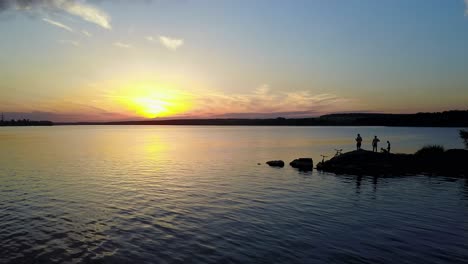 people relaxing on a river bank, enjoying the riverside sunset