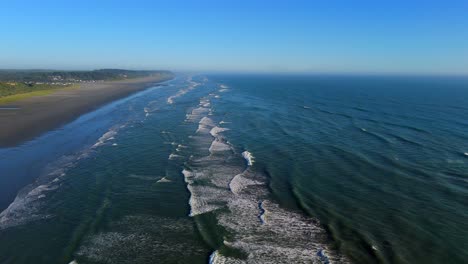 Scenic-high-aerial-shot-of-ocean-waves-and-beach-of-the-Pacific-Ocean-during-daytime-with-blue-sky