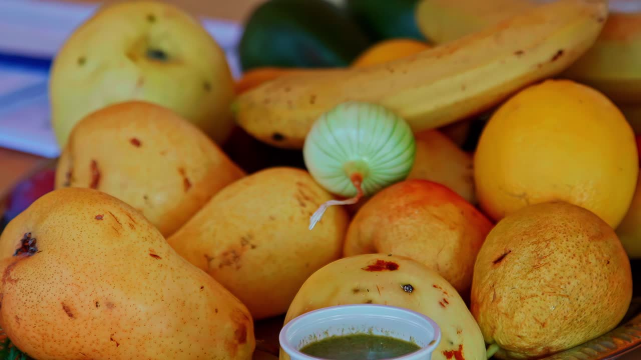 Tray of ripe mangoes with herbs and green juice cup on wooden table