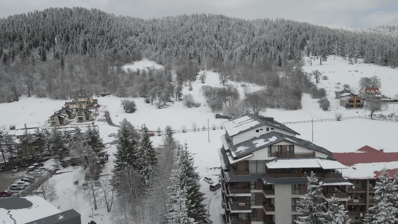 An aerial view of a bustling ski resort, showcasing ski runs and snow-covered buildings