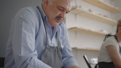 portrait of a male potter making a ceramic plate in slow motion