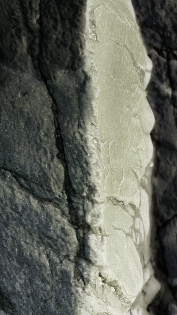 Close up view of a textured rock surface showing cracks and lines