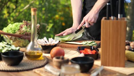 medium shot of a male cutting zucchini into long slices in his garden