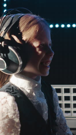 laughing child in audio record studio. happy little girl has fun preparing to perform song in professional mic in insulated room. young vocalist