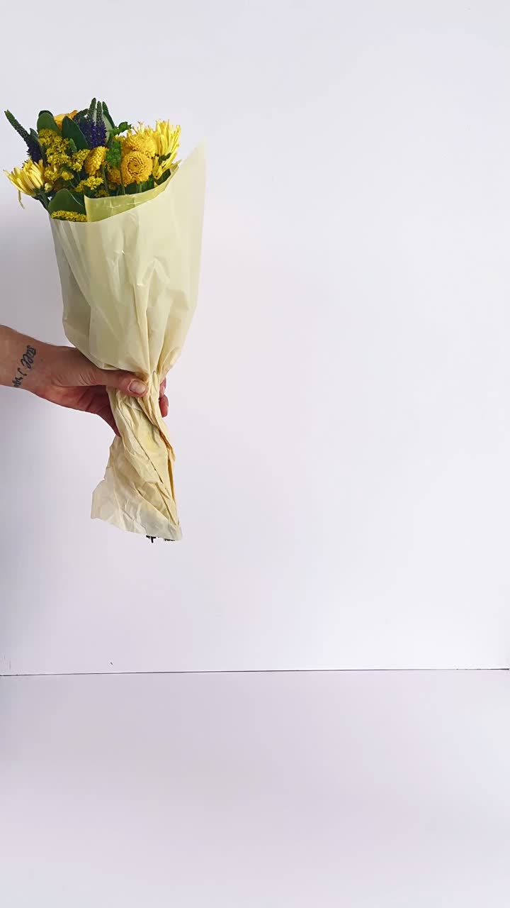 Hand holding a bouquet of yellow and purple flowers