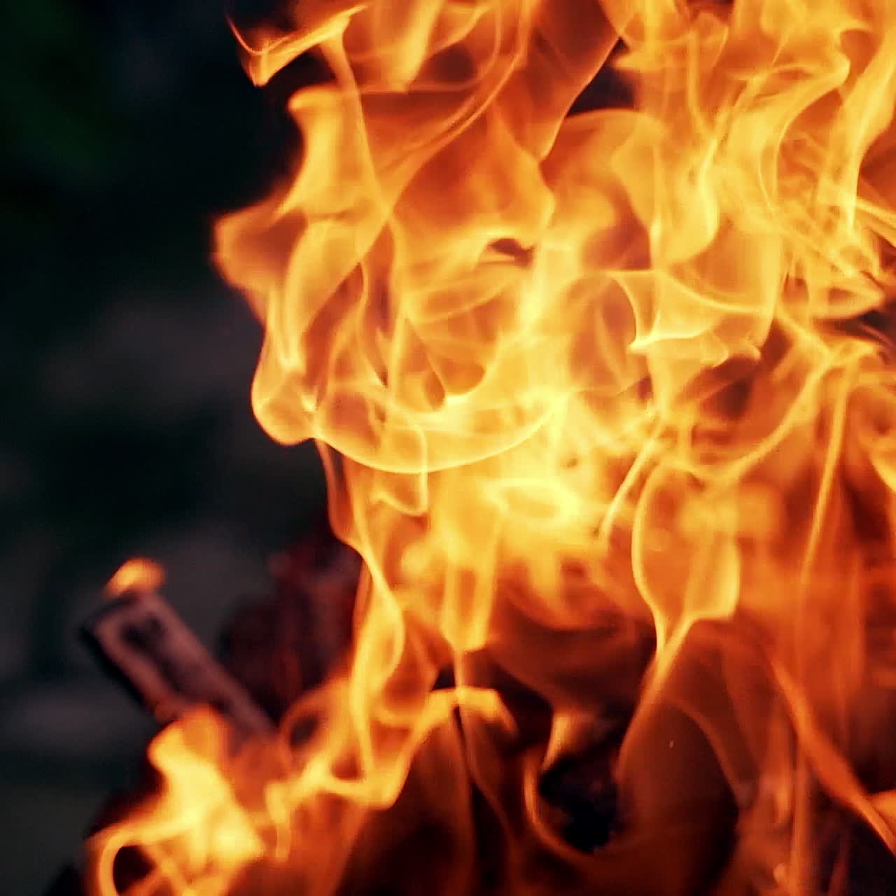 a burning and sparking campfire at night with burning woods.