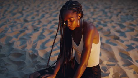 beautiful young black woman with braids and golden earrings, basking in the warm glow of sunset light on a beach, closing her eyes and embracing a moment of pure relaxation