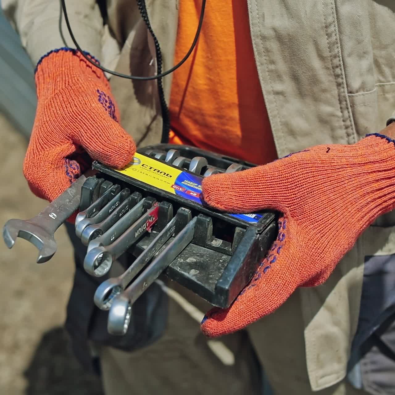Instruments in worker's hands. Technician man is taking tools for constructing solar panels. Close-up. Slow motion.