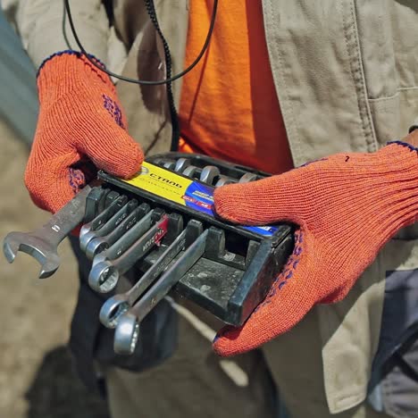 instruments in worker's hands. technician man is taking tools for constructing solar panels. close-up. slow motion.