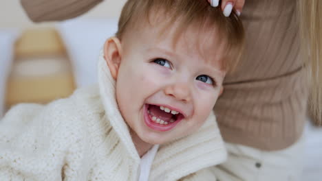 unrecognized blonde woman plays with her little son. mother touches and tickles her baby boy and kid is happy.