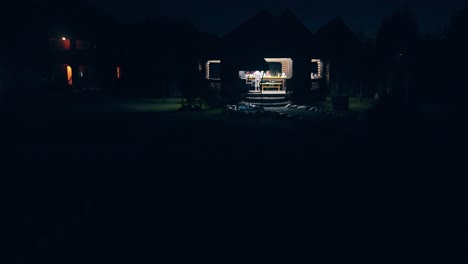 family rests at night under a wooden roof in a summer house on a picnic