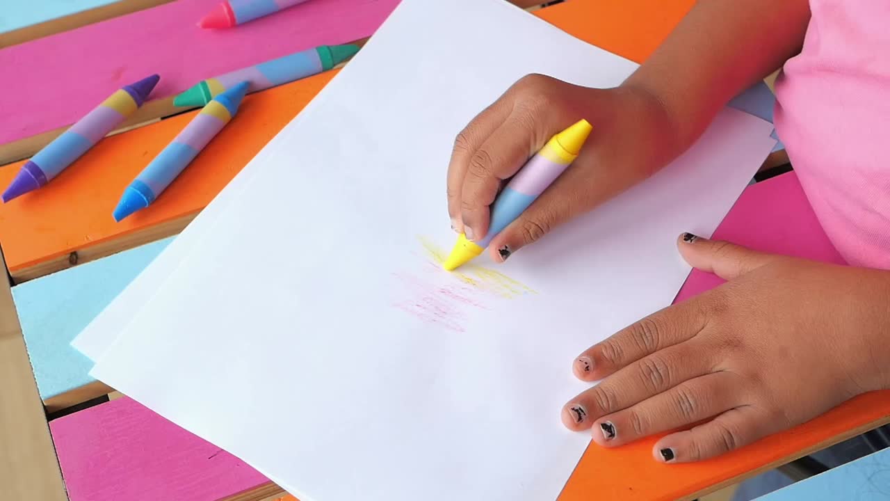 Child's Hand Drawing with a Yellow Crayon on White Paper