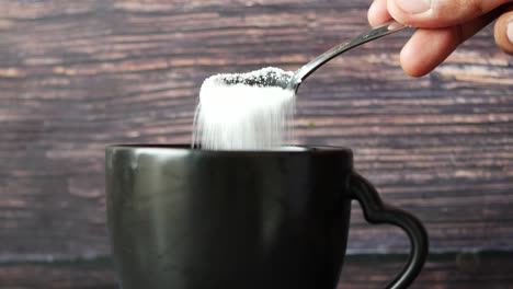 Pouring-white-sugar-in-a-coffee-cup