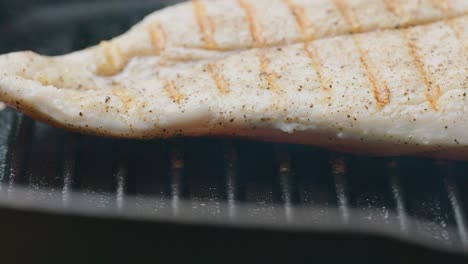 flipping juicy chicken fillet on hot grill during cooking