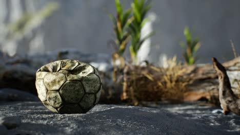 an old torn soccer ball thrown lies on sand of sea beach