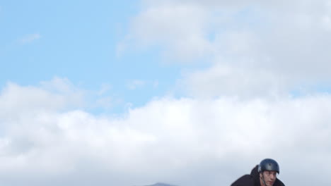 extreme sport mountain biking. a young man on a bike dirt jumping in slow motion.  blue sky and scattered clouds in the background.
