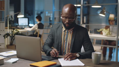 african american businessman working with papers late in office