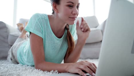 mujer bonita acostada en el suelo usando su computadora portátil