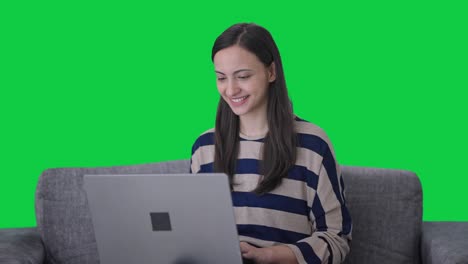 chica india feliz usando la pantalla verde del portátil