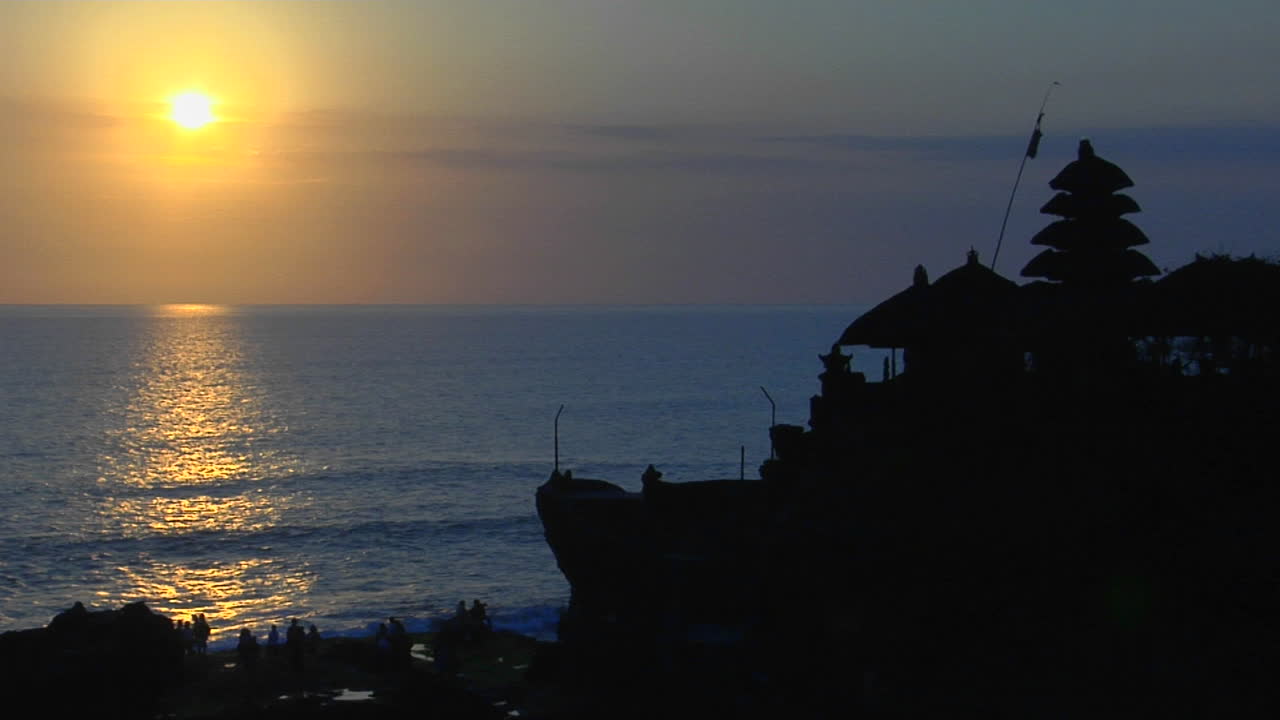 인도네시아 발리의 푸라 타나 로트 사원 근처의 물 위에 태양이 빛난다