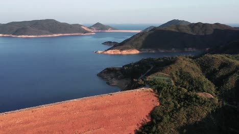 Movimiento-Aéreo-Hacia-Atrás-Disparado-Sobre-La-Presa-Que-Conecta-Dos-Islas-En-El-Parque-Geográfico-De-Hong-Kong-En-Sai-Kung-En-Un-Hermoso-Día-Soleado