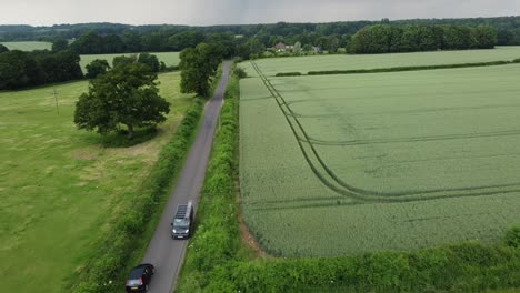 a drone following shot following a very fast car speeding down a quiet country lane,having to slam on the breaks to let another car past, shot on a very overcast and cloudy day