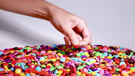 hand selecting candies from a colorful pile