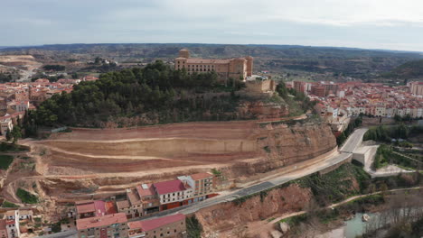 Aerial-flight-around-Alcañiz-parador-on-a-rocky-hill-Spain-cloudy-day-old