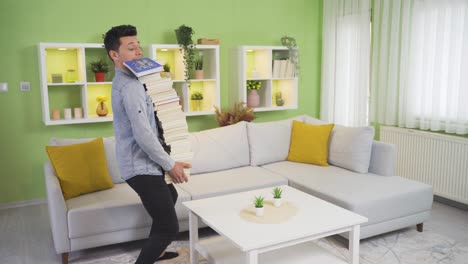 Clumsy-young-man-drops-a-pile-of-books-at-home.