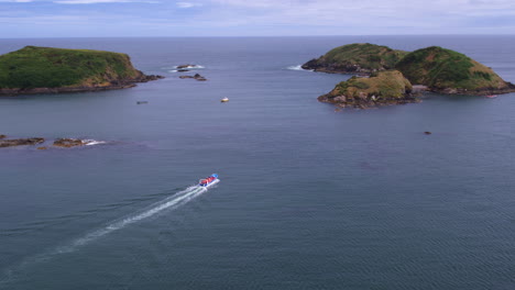 paisaje aéreo de un barco que viaja alrededor de la isla costera en la costa de punihuil, isla de chiloé, día soleado