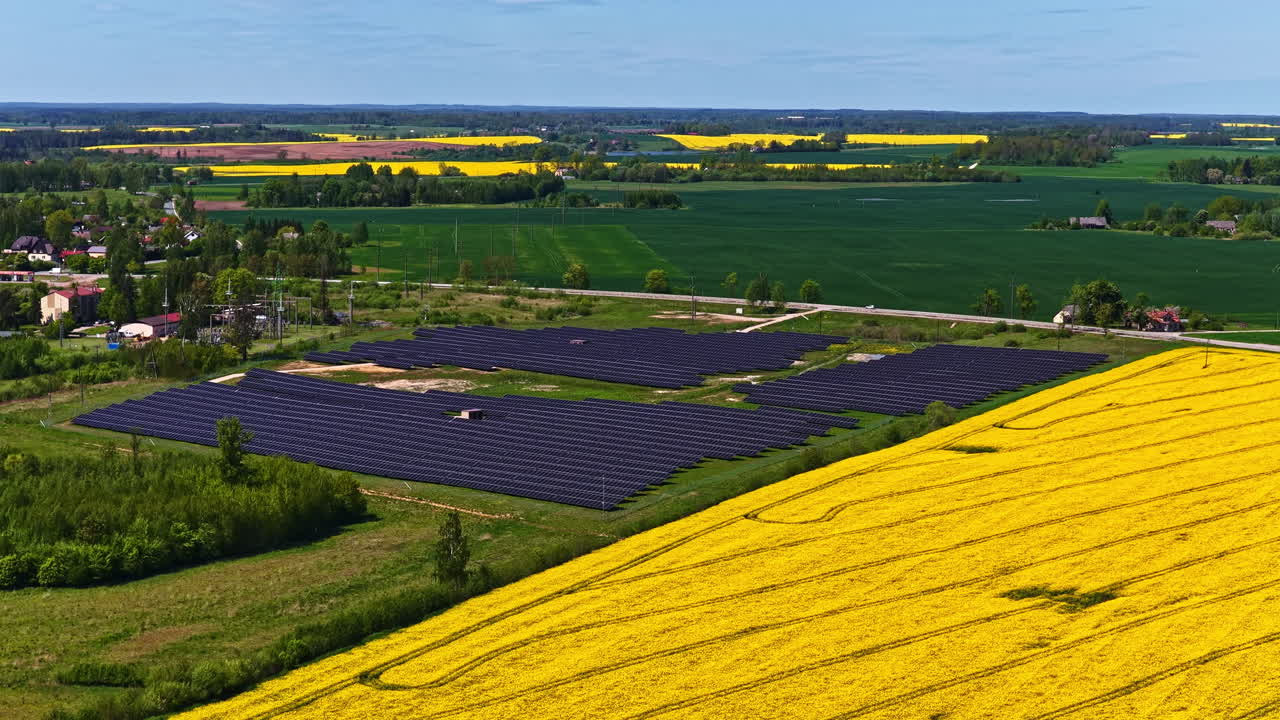 Clear blue sky above photovoltaic cell farm and bright yellow rapeseed field