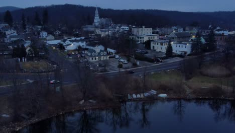 Eine-Kleine-Stadt-Am-See-Im-Winter-Und-Herbst-Kurz-Nach-Sonnenuntergang,-Mit-Häusern-Und-Autos-Und-Einem-Bedeckten-Himmel-Und-Verkehr