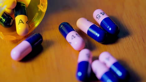 Prescription-bottle-filled-with-pink-and-blue-pills-spills-in-slow-motion-to-scatter-contents-close-to-the-camera's-macro-lens