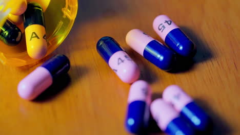 prescription bottle filled with pink and blue pills spills in slow motion to scatter contents close to the camera's macro lens