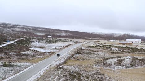 winter road trip driving in the nature alongside trees and snow in dovre, norway - aerial drone shot