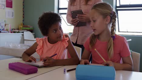 two girls talking to each other while studying in the class
