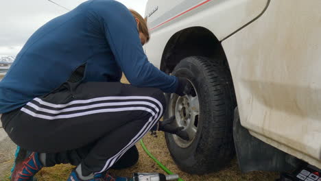 Close-up-shot-of-a-men-mounting-summer-tire-after-winter-season-on-a-cloudy-day