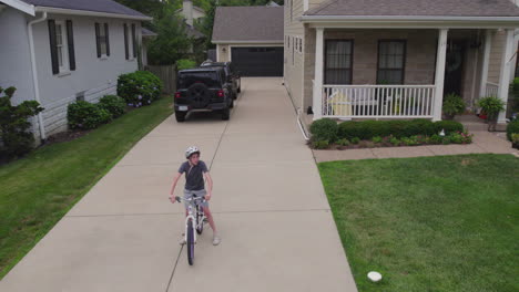 boy on his bike waits at the end of the driveway at his house