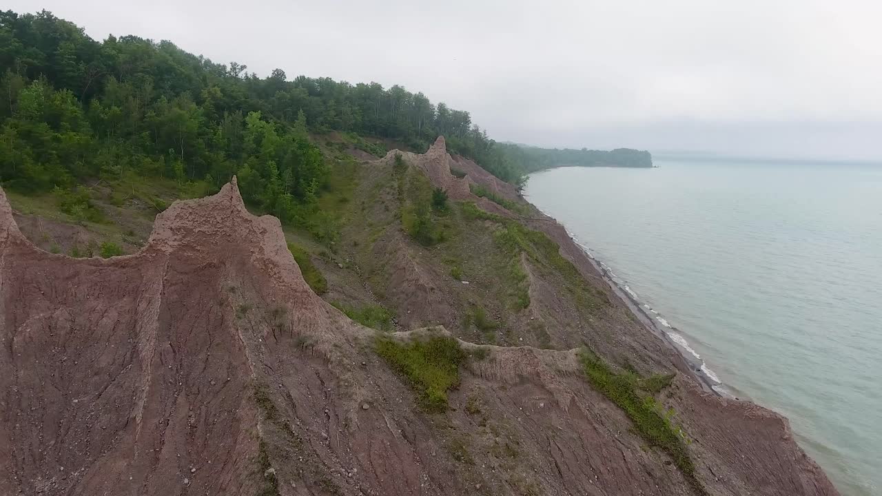 A 4K drone shot over the large clay formations of Chimney Bluffs State Park, on the water's edge of Lake Ontario, in the town of Huron, New York