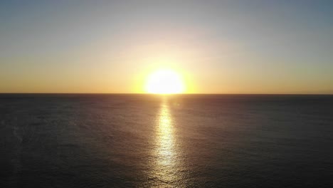 Aerial-View-Of-Golden-Yellow-Sunset-Over-The-Ocean-Water-Towards-Horizon