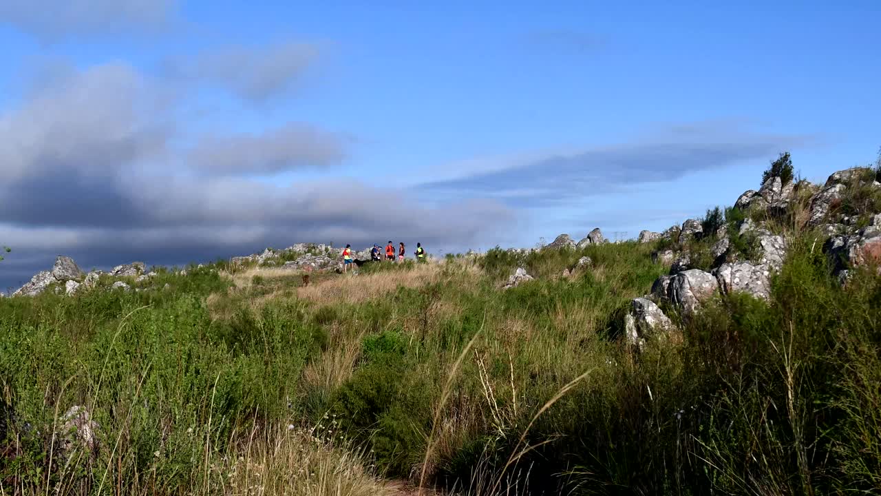 Hikers Trekking On The Lush Rocky Trail In Sierra Tandil In Argentina On A Bright Windy Day - Time Lapse