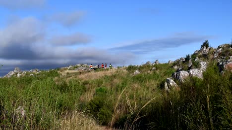 hikers trekking on the lush rocky trail in sierra tandil in argentina on a bright windy day - time lapse