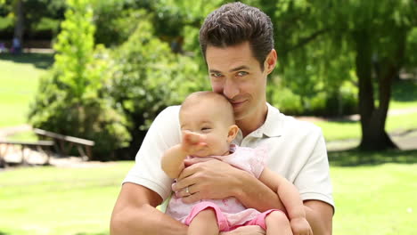 padre feliz sosteniendo a su niña en el parque