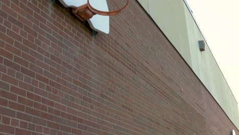 basketball hoops on a red brick wall of a schoolyard