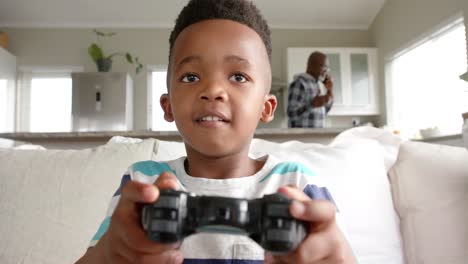 African-american-boy-sitting-on-sofa-and-playing-video-games,-slow-motion