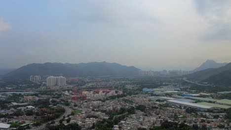 Urbanization-of-the-countryside-landscape-with-buildings,-houses-and-a-city-in-the-distance-during-the-day