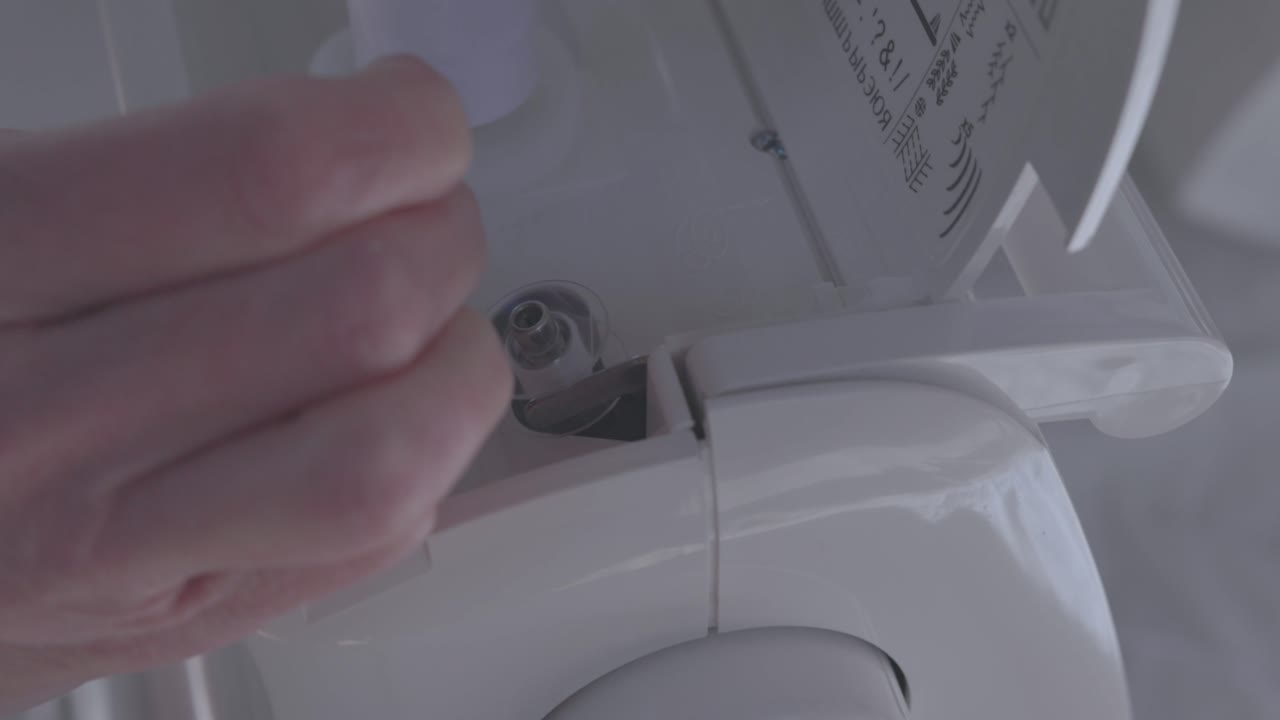 bobbin being threaded with white thread on a sewing machine