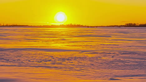 Tiro-De-Lapso-De-Tiempo-De-La-Puesta-De-Sol-Detrás-De-Los-árboles-Sobre-El-Campo-Blanco-Congelado-En-La-Fría-Noche-De-Invierno