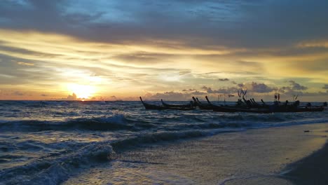 Paisaje-Marino-Al-Atardecer-En-La-Isla-De-Koh-Lanta,-Barcos-De-Pesca-De-Madera-En-Reposo-En-Medio-De-Suaves-Olas-En-La-Playa,-Tailandia